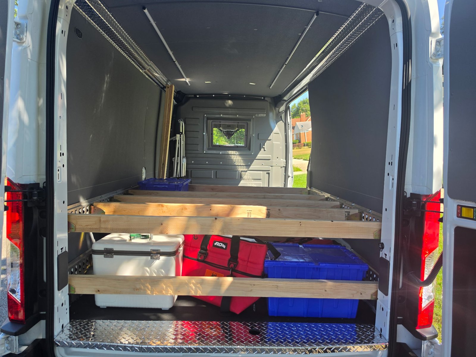 2026 Ford Transit 250 — rear cargo view showing E-Track walls, wooden shelving with equipment, composite non-porous floor, and aluminum sill kit