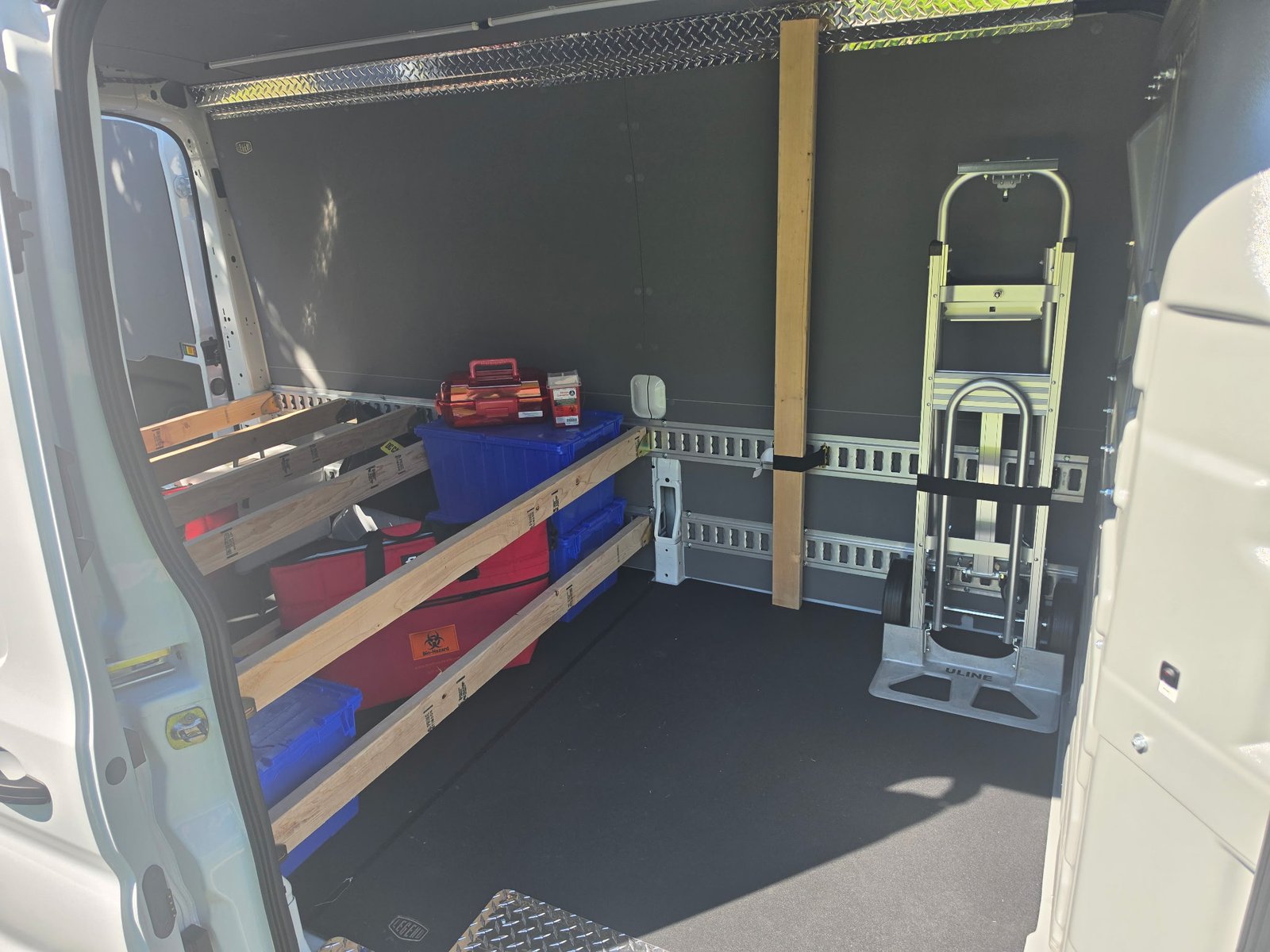 2026 Ford Transit 250 — side door view showing biohazard containment, strap-secured hand truck, dual-height E-Track rails